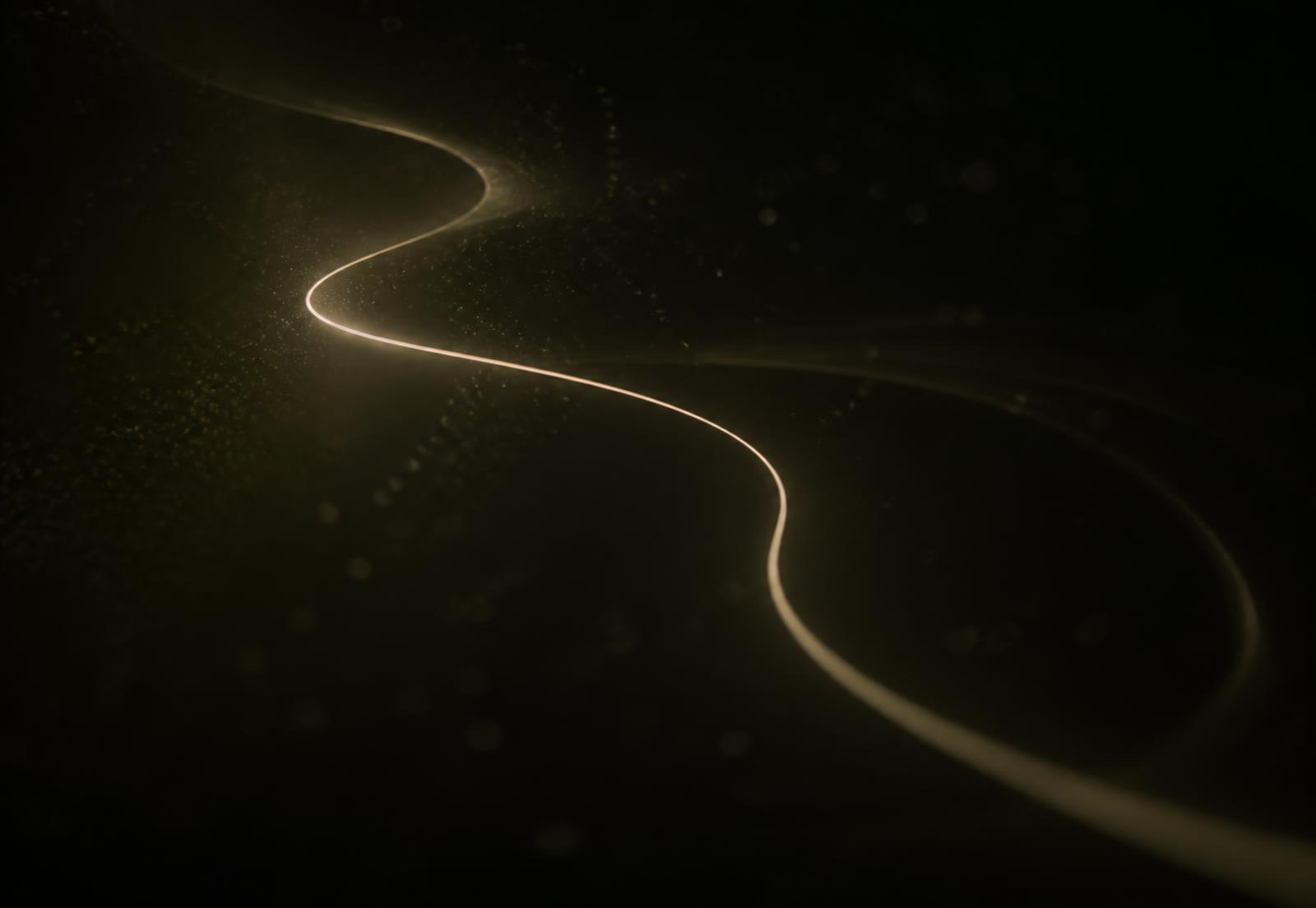 Long exposure light trail curving softly through darkness
